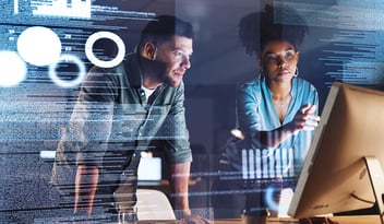 Colleagues looking at a computer with lines of code on